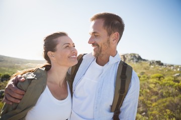 Hiking couple embracing and smiling on country terrain