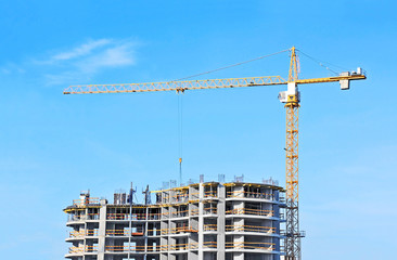Crane and building construction site against blue sky