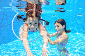 Happy active kids play underwater in swimming pool