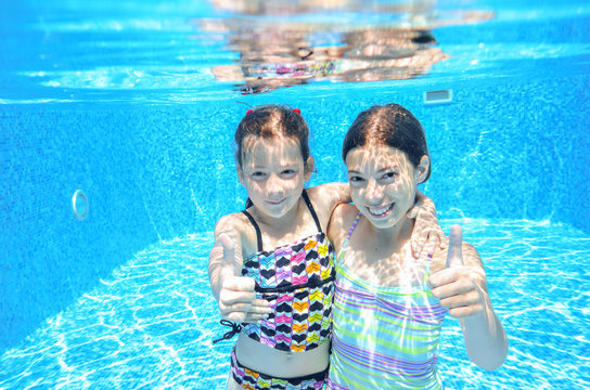 Happy active kids play underwater in swimming pool