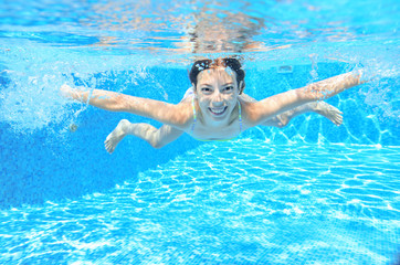 Active underwater child swims in pool, girl swimming