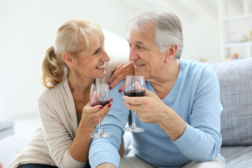 Cheerful senior couple cheering with glass of wine