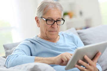 Fototapeta na wymiar Senior man reading news on digital tablet