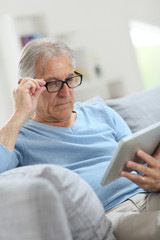 Senior man reading news on digital tablet