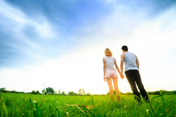couple walking through the field and holding hands