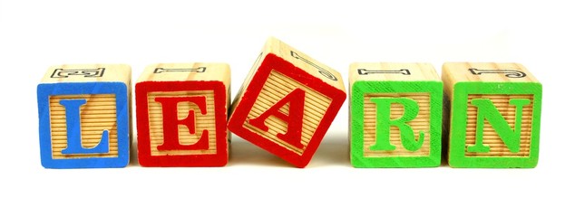 Toy wooden blocks spelling LEARN over a white background