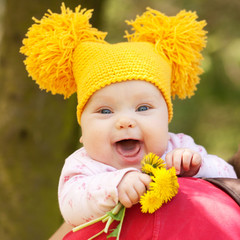 baby in yellow knitted cap with dandelions