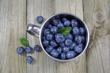 blueberries in metal cup on wooden background