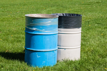 Two garbage bins on green grass.