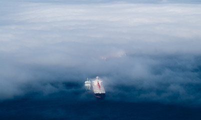 Cargo ships emerging from fog.