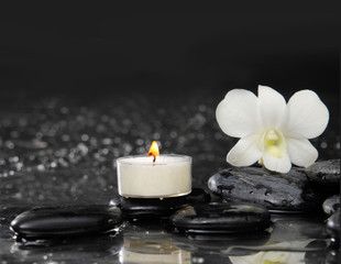 Spa still life with white orchid and candle on pebbles