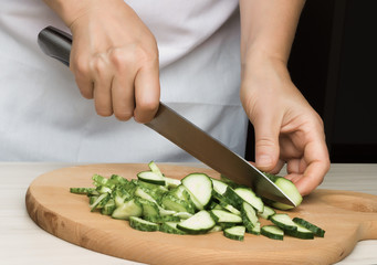 Woman's hand slicing a cucumber.