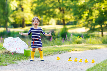 Naklejka premium Beautiful little girl of 2 playing with yellow rubber ducks in s