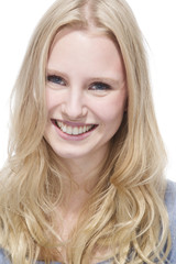 Fototapeta premium Junge blonde Frau lächelt gegen weisser Hintergrund, Porträt