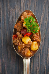 spicy Mexican dish chili con carne in a spoon, conceptual photo