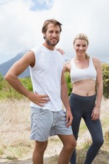 Attractive fit couple standing on mountain trail