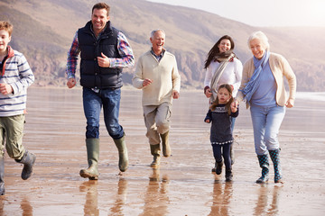 Multi Generation Family Running On Winter Beach