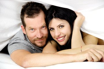 Happy couple in love smiling in bed