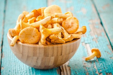 fresh chanterelle mushrooms in a bowl on a wooden background