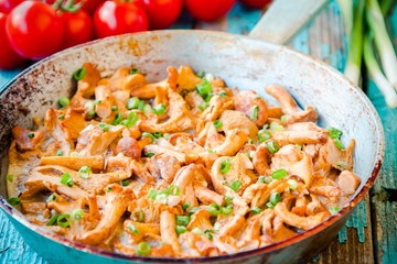fried chanterelle mushrooms with green onions in a frying pan