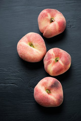 Saturn peaches over black wooden background, above view