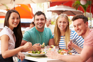 Fototapeta na wymiar Group Of Friends Enjoying Lunch In Outdoor Restaurant
