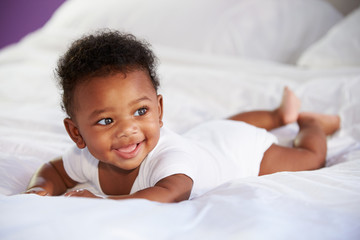 Cute Baby Lying On Tummy In Parent's Bed - obrazy, fototapety, plakaty