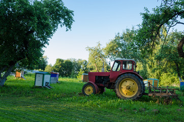 rural farm tractors in summer garden to the hive
