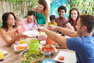 Group Of Families Enjoying Outdoor Meal At Home