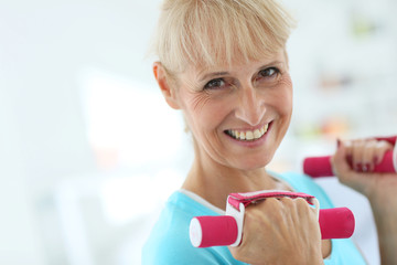 Portrait of senior woman lifting dumbbells
