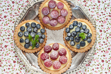 Heidelbeer- und Himbeertörtchen auf einem Silbertablett