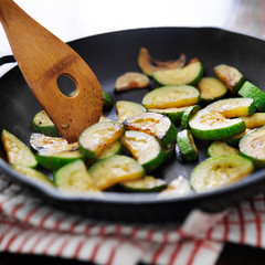 stirring fried zucchini in an iron skillet