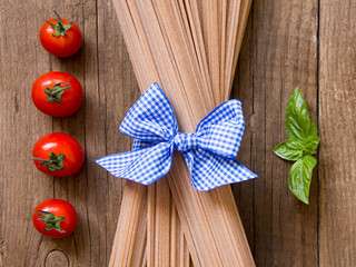 Pasta, tomatoes and basil on wooden background