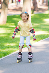 Fototapeta premium Little girl rollerskating in the park