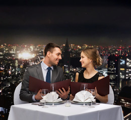 smiling couple with menus at restaurant