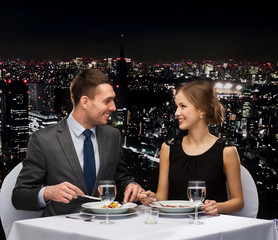 smiling couple eating main course at restaurant