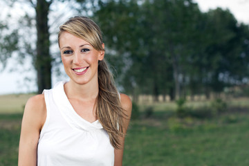 happy woman posing in the field on a background of trees