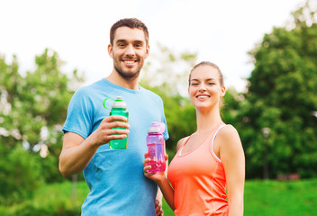 smiling couple with bottles of water outdoors