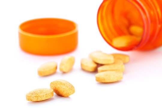 Closeup of orange pills and pill bottle