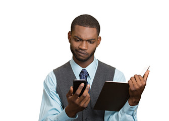 Skeptical man looking at phone holding book, unhappy