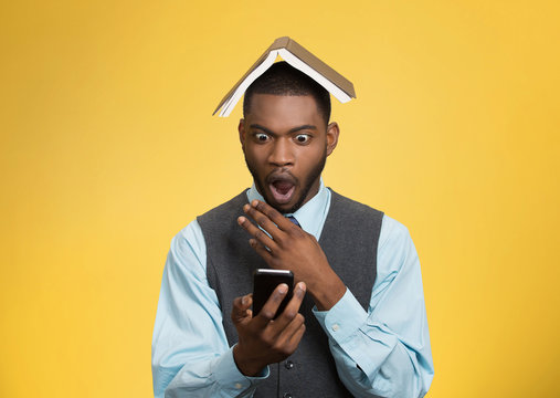 Shocked man holding smart phone, reading news, book over head