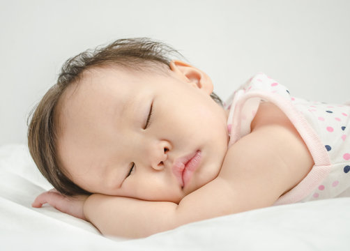 Asian baby girl sleeping on bed