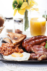 Full English breakfast with bacon, sausage, egg, beans and juice