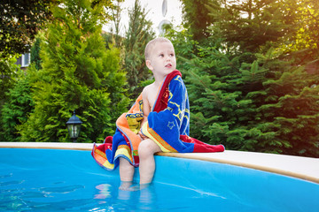 Cute child with towel on edge of swimming pool