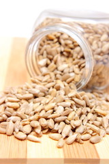 Heap of sunflower seeds in glass jar on wooden cutting board