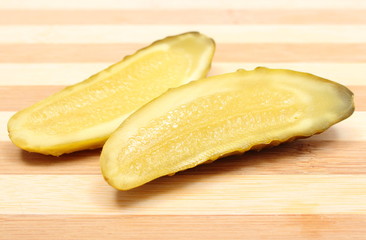 Marinated pickled cucumber lying on wooden cutting board