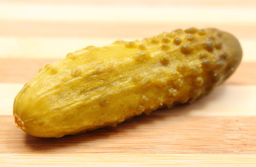 Marinated pickled cucumber lying on wooden cutting board