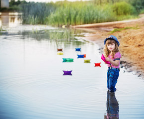 Naklejka premium smile child playing with paper boats in a river