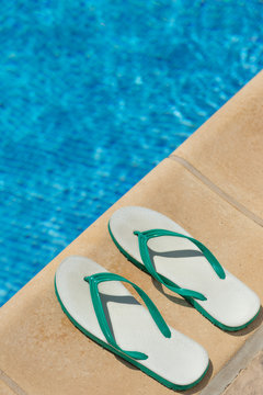 Pair of flip flop thongs and a towel on the side of a swimming