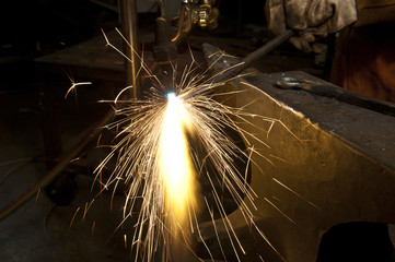 A metal fabricator utilizing a torch to heat up a piece of metal in order to shape it.